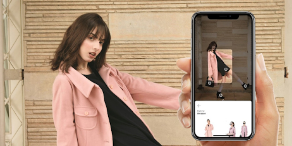 A woman displays a smartphone showing a photo of another woman wearing a pink coat, highlighting visual search technology.